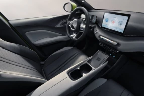 Modernes Interieur des Fahrzeugs mit hellgrauen Sitzen, zentralem Touchscreen und aufgeräumter Mittelkonsole.
