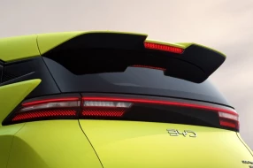 Heck eines leuchtgelben Fahrzeugs mit durchgehender LED-Rückleuchte und markantem Dachspoiler bei Tageslicht.