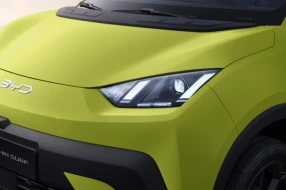 Nahaufnahme der Frontpartie des BYD Dolphin Surf in leuchtendem Gelb, mit markantem LED-Scheinwerferdesign und BYD-Logo.