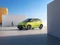 Limegrüner BYD-Kleinwagen vor Hintergrundsilhuette mit Kaktus.