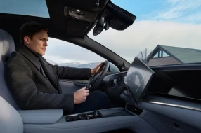 Ein Fahrer sitzt in einem Auto, während sich das Multimedia-Display elektrisch in das Hochformat schwenk.