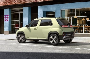 Hellbeiger Hyundai Inster in Seitenansicht, parkend vor einem Café.