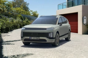 Moderner Elektro-SUV parkt vor Haus mit Ladestation.