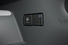 Nahaufnahme einer Steckdose mit Schutzkontakt und einer daneben liegenden Steckdose mit dem Symbol für Elektrofahrzeuge.