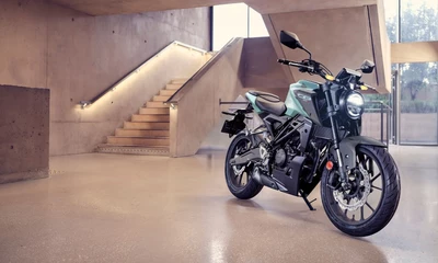 Eine Honda CB125R vor einer Treppe in einem Gebäude.