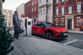 Roter Hyundai IONIQ beim Aufladen, zwei Menschen stehen daneben im Gespräch,