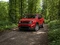 Roter Jeep auf einer Waldstraße.