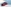 Roter Opel Corsa parkend vor einer grauen Wand, frontal seitlich.