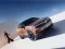 Opel Grandland Electric steht auf weißer Fläche, Frau läuft auf das Elektro-SUV zu.