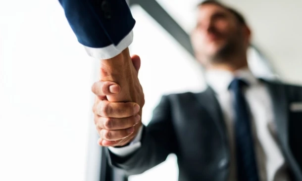 Zwei Personen im Business-Outfit geben sich zur Begrüßung oder Einigung die Hand.