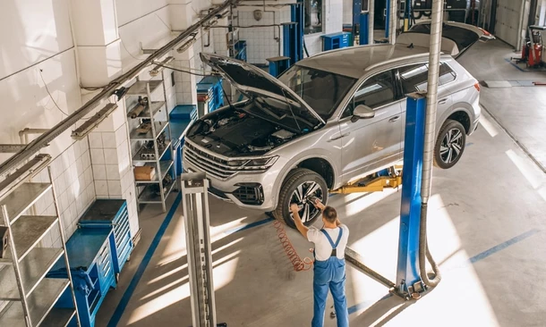 Fahrzeug auf Hebebühne in der Werkstatt – Mechatroniker überprüft Reifen und Fahrwerk.