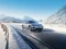 BYD Limousine fährt dynamisch durch verschneite Winterlandschaft.