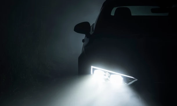 Silhouette eines Fahrzeugs mit eingeschaltetem LED-Scheinwerfer – kühler Lichtstrahl sorgt für Sichtbarkeit bei Dunkelheit.