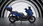 Blaue Honda Forza 125 vor einem schwarz-weißen Hintergrund, seitlich.