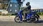 Blaue Honda SH125i fahrend durch eine Stadt, seitlich.