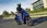 Blaue Honda SH125i fahrend durch eine Stadt.