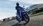 Blaue Honda SH125i fahrend durch eine Stadt.