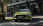 Limettengrüner Hyundai i20 fährt durch eine Stadt, frontal.