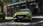 Limettengrüner Hyundai i20 fährt durch eine Stadt, frontal.