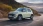 Ein buttergelber Hyundai Inster fährt dynamisch auf einer kurvigen Straße.