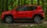 Roter Jeep auf einem Waldweg, seitlich.