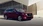 Roter Mazda vor einer gläsernen Wand, seitlich-frontal.