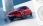 Roter Opel Corsa zwischen zwei weißen Musikboxen, frontal-seitlich.