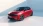 Ein roter Opel Corsa vor einer weißen Kulisse, frontal-seitlich.