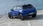 Blauer Opel Mokka vor einem Meer, von hinten fotografiert.