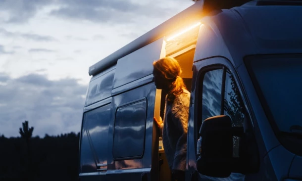 Etrusco Freizeitmoil bei Nacht mit geöffneter Schiebetür – eine Person steht im Lichtschein des Tür-Spots, bereit für den Abend am Stellplatz.