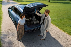 Geparktes BYD Fahrzeug in Blau, Paar steht vor geöffneter Heckklappe.