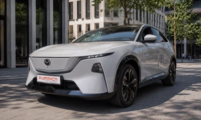 Grauer Mazda-SUV in einer Stadtkulisse, frontal.