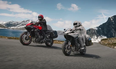 Zwei Honda-Motorräder fahren durch ein Alpenpanorama.