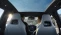 Paar im Auto genießt Panoramadach und Ausblick im komfortablen Innenraum eines modernen Elektroautos.