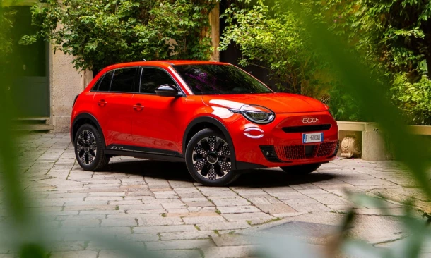 Roter Pkw parkt in einem bepflanzten Hinterhof.