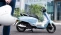 Person mit Helm in der Hand läuft auf Motorrad zu.