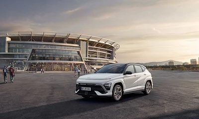 Ein weißes Hyundai Fahrzeug parkt in Frontalansicht vor einem Stadion.