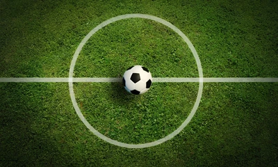 Blick auf einen Fußball auf einem Fußballrasen aus der Vogelperspektive.