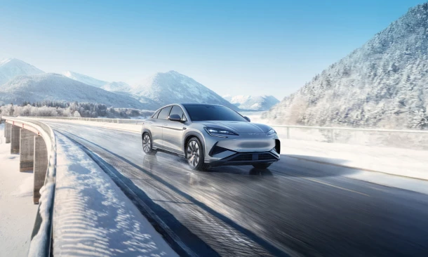 Sportwagen fährt dynamisch durch eine Winterlandschaft.