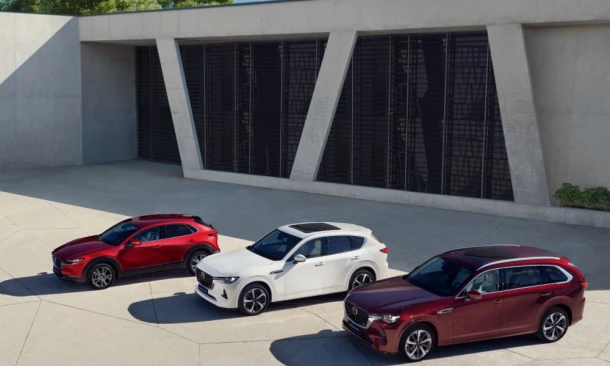 Drei Fahrzeuge der Mazda-Familie parken auf einem Vorplatz aus Stein.