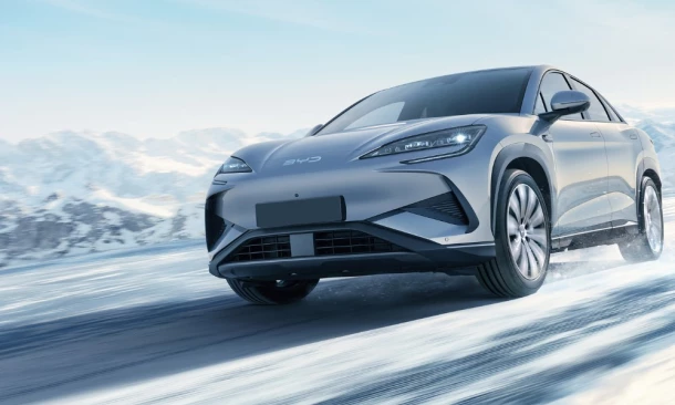 Eine BYD Limousine fährt dynamisch durch eine verschneite Winterlandschaft.