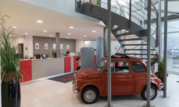 Moderner Empfangsbereich am Kummich Standort Aalen mit Fiat 500 Oldtimer und Wendeltreppe.