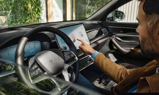 Ein Mann sitzt am Steuer eines BYD City-SUV und bedient den Display des drehbaren Kombiintruments.