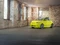 Gelber Abarth geparkt vor einer industriellen Mauer.