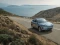 BYD SUV in dynamischer Fahrt auf Landstraße mit Wasserlandschaft.